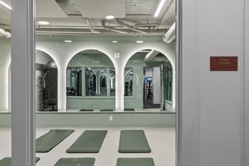 Yoga studio with green mats and mirrored arches